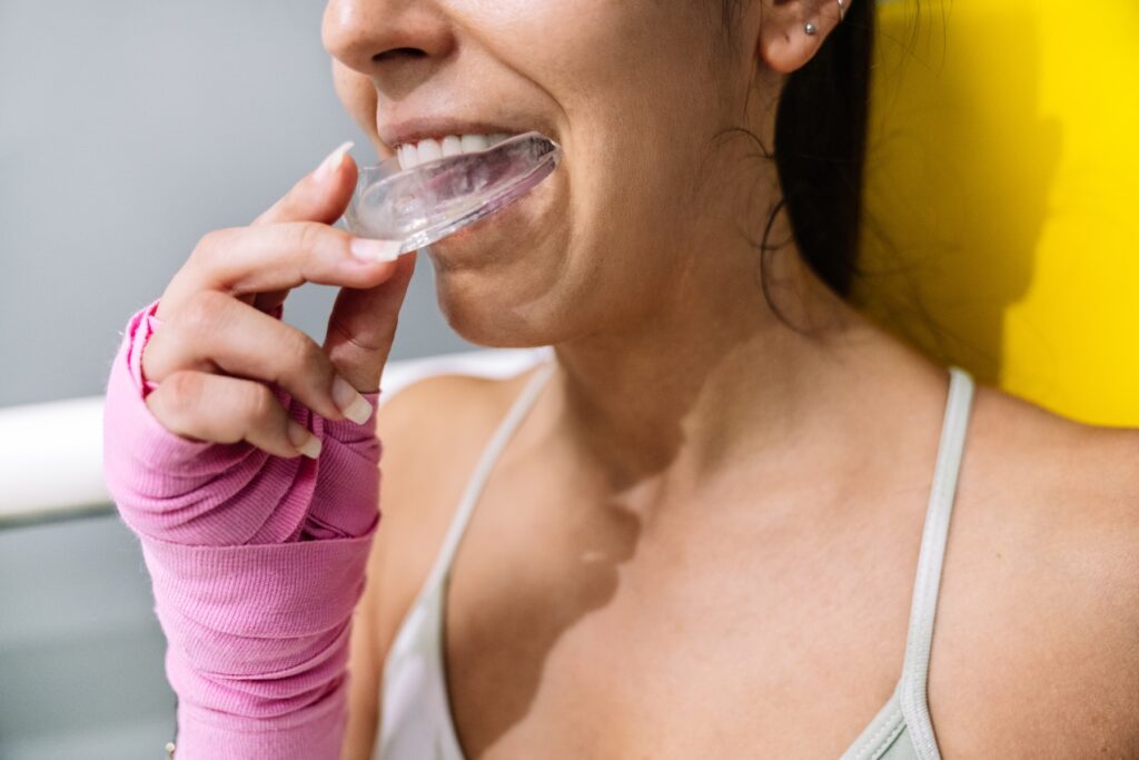 Midsection of an athlete putting on a mouth guard in boxing training in a ring.